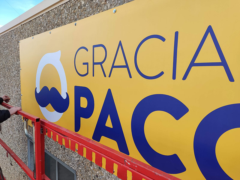 lona publicitaria instalada sobre fachada con tornillería