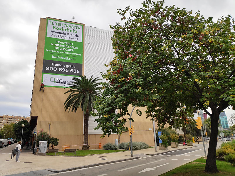 instalación de lona publicitaria sobre fachada mediante trabajo vertical