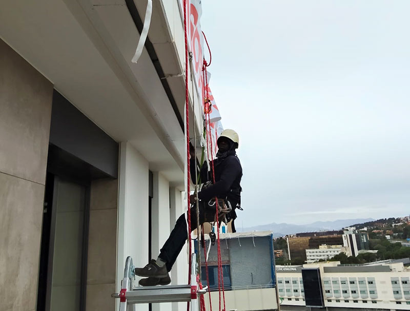 publicidad instalada por operario con trabajos verticales